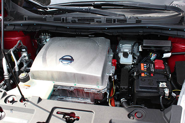 Hier sieht man rechts die Starterbatterie, der Stromspeicher für die Elektromotoren ist im Fahrzeugboden untergebracht. Hier sieht man den Motorraum eines Nissan Leaf.